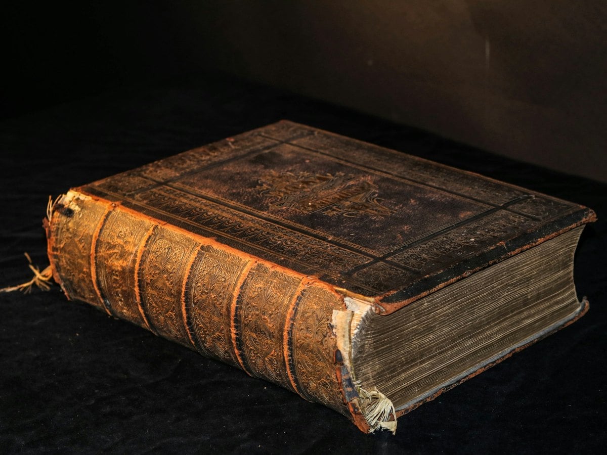 Ouvrage ancien relié en cuir posé sur une table sombre