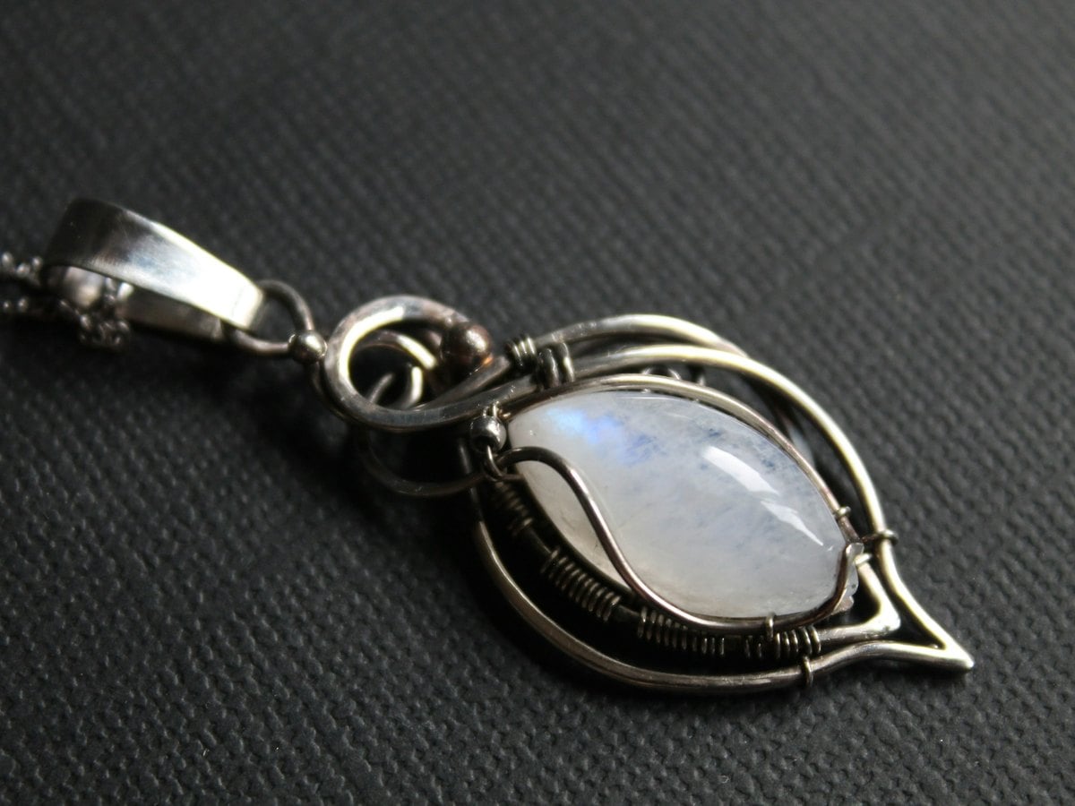 Pierre de lune taillée en cabochon et sertie en pendentif : reflet bleu d'adularescence